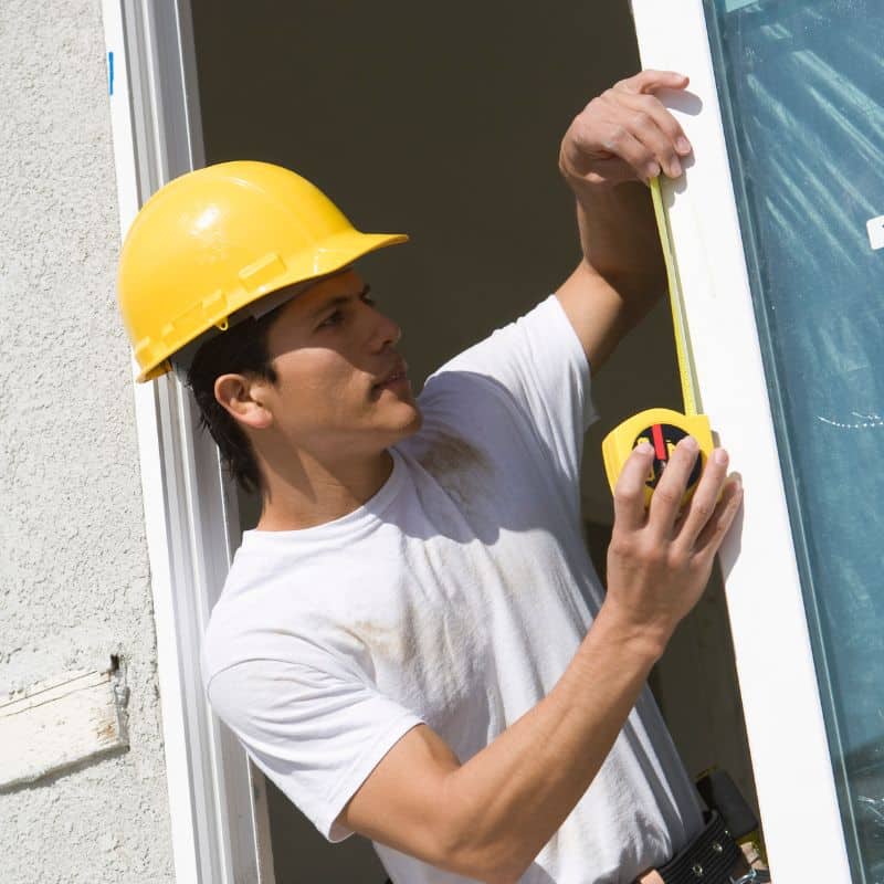 tech checking height measurements on a window
